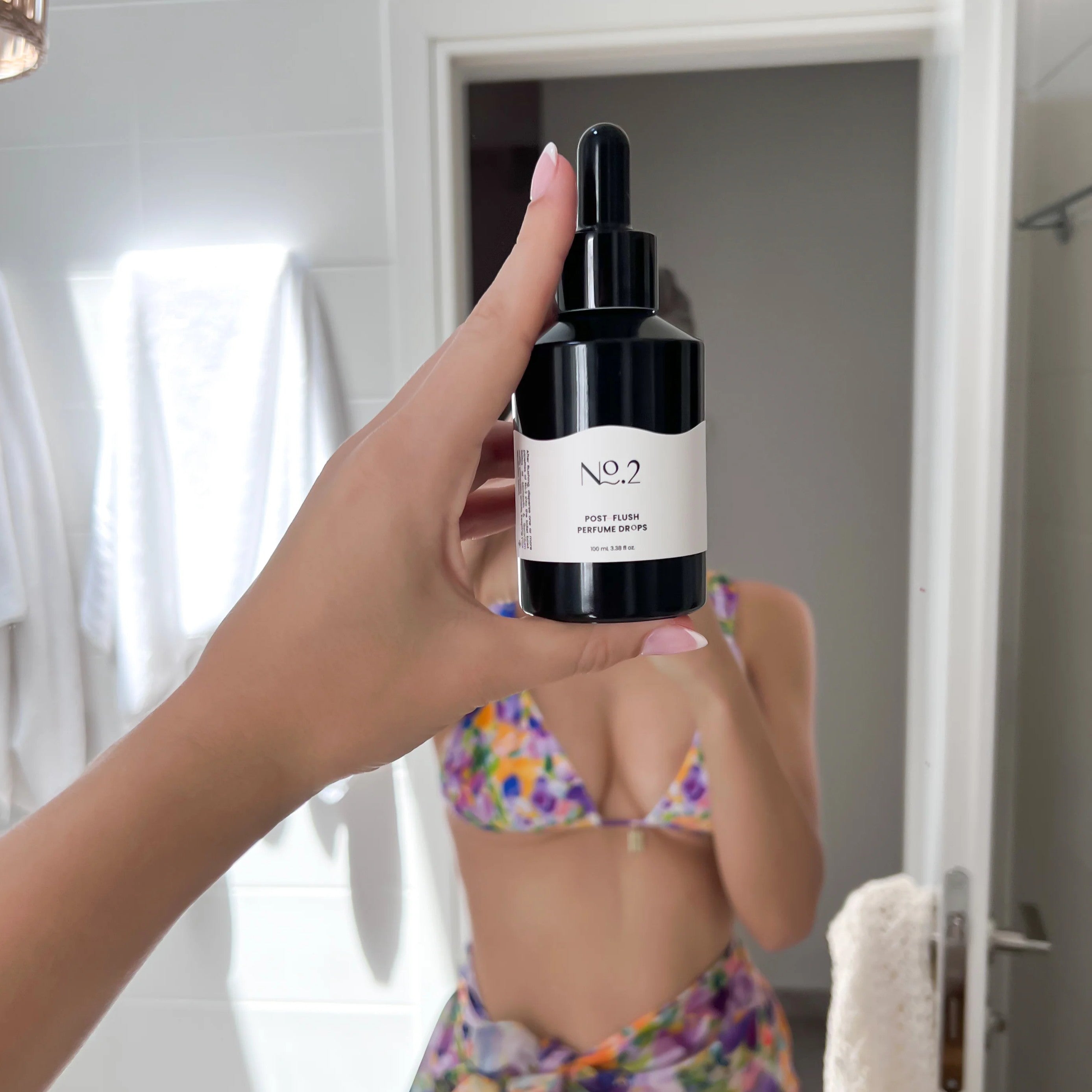 Hand holding a black dropper bottle labeled &